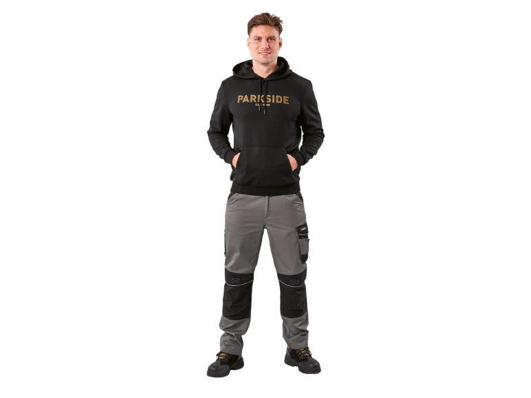 Muškarac u crnom duksu sa kapuljačom i sivo-crnim radnim pantalonama.