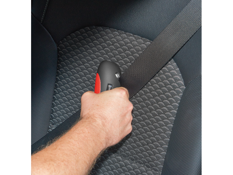 Muška ruka drži alat za sečenje sigurnosnog pojasa u automobilu.