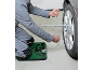 Muškarac menja gumu na automobilu koristeći krstasti ključ i podlogu za klečanje.
