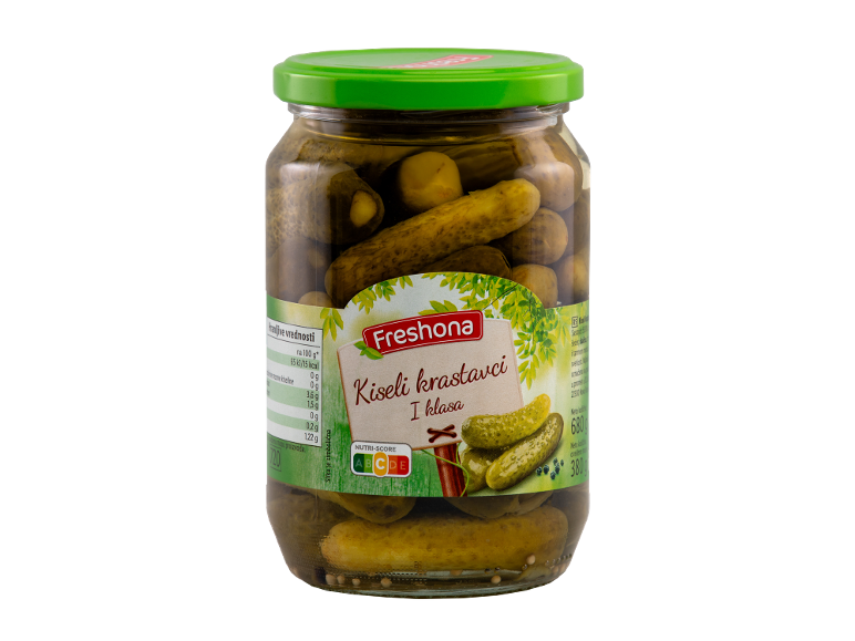 Staklena tegla kiselih krastavaca, sa zelenim poklopcem i etiketom sa nutritivnim vrednostima.