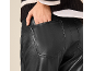 Žena u crnim kožnim pantalonama i prugastom džemperu, ruka u džepu.