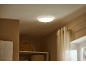 Okrugla plafonska lampa osvetljava sobu sa zavesama i policama za odlaganje.