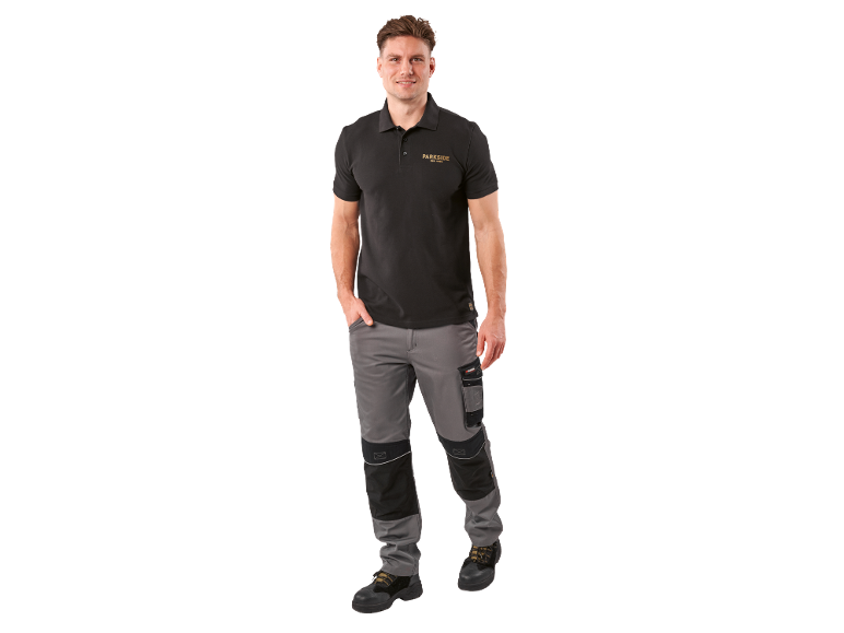 Muškarac u crnoj polo majici sa logom i sivim radnim pantalonama.