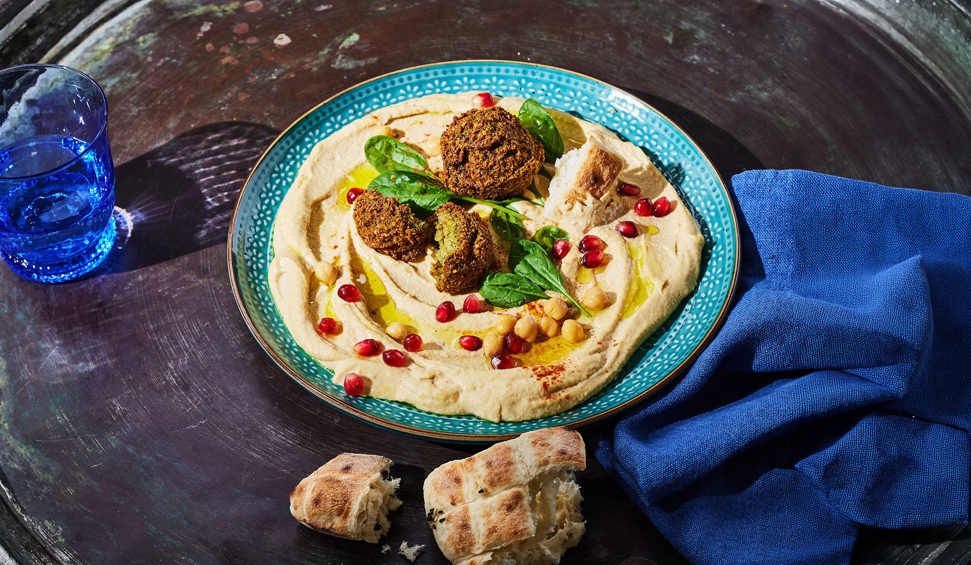 Humus sa falafelom, semenkama nara i pita hlebom na tamnom stolu.