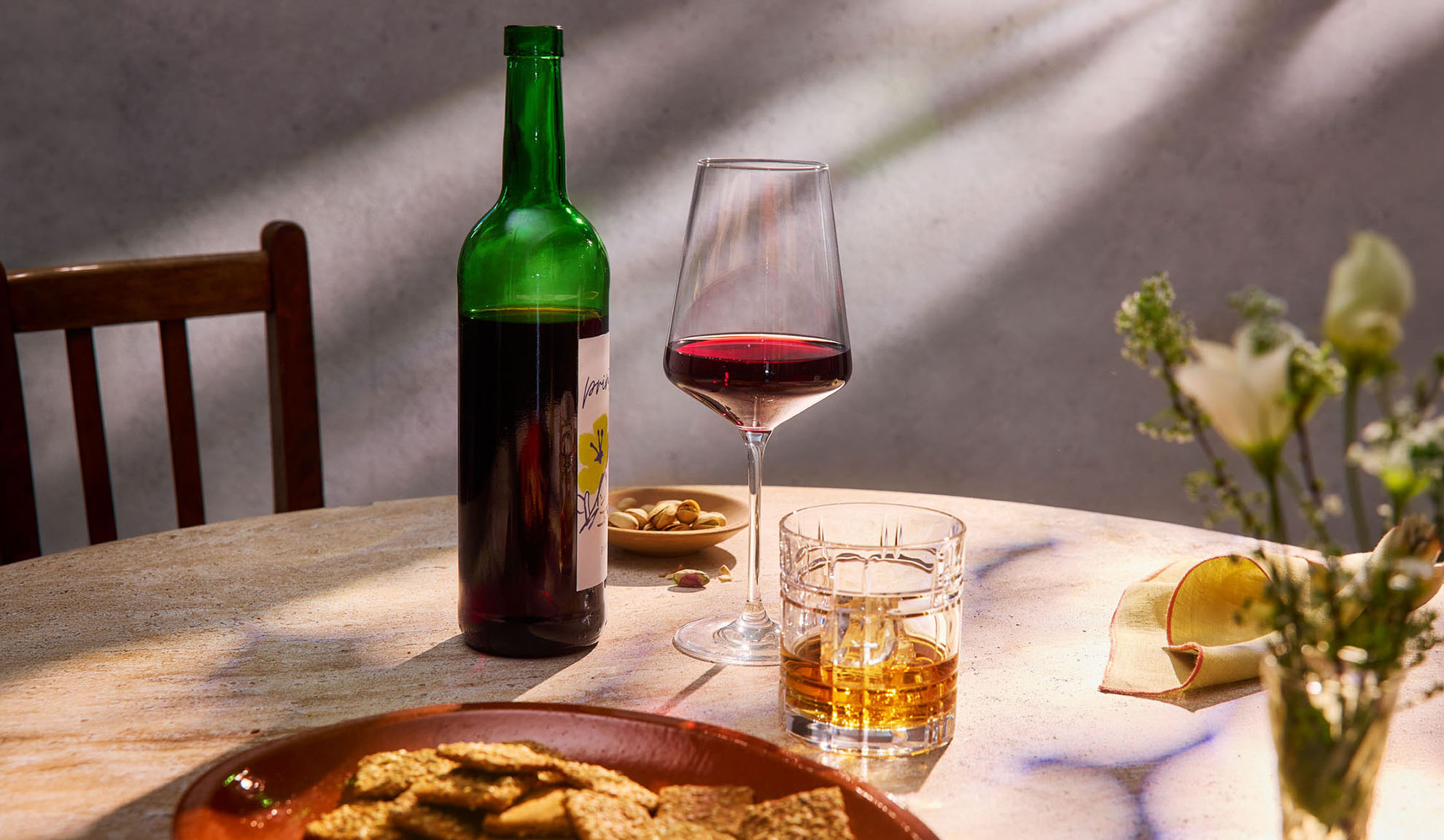 Crveno vino, viski i grickalice na stolu obasjanom suncem.