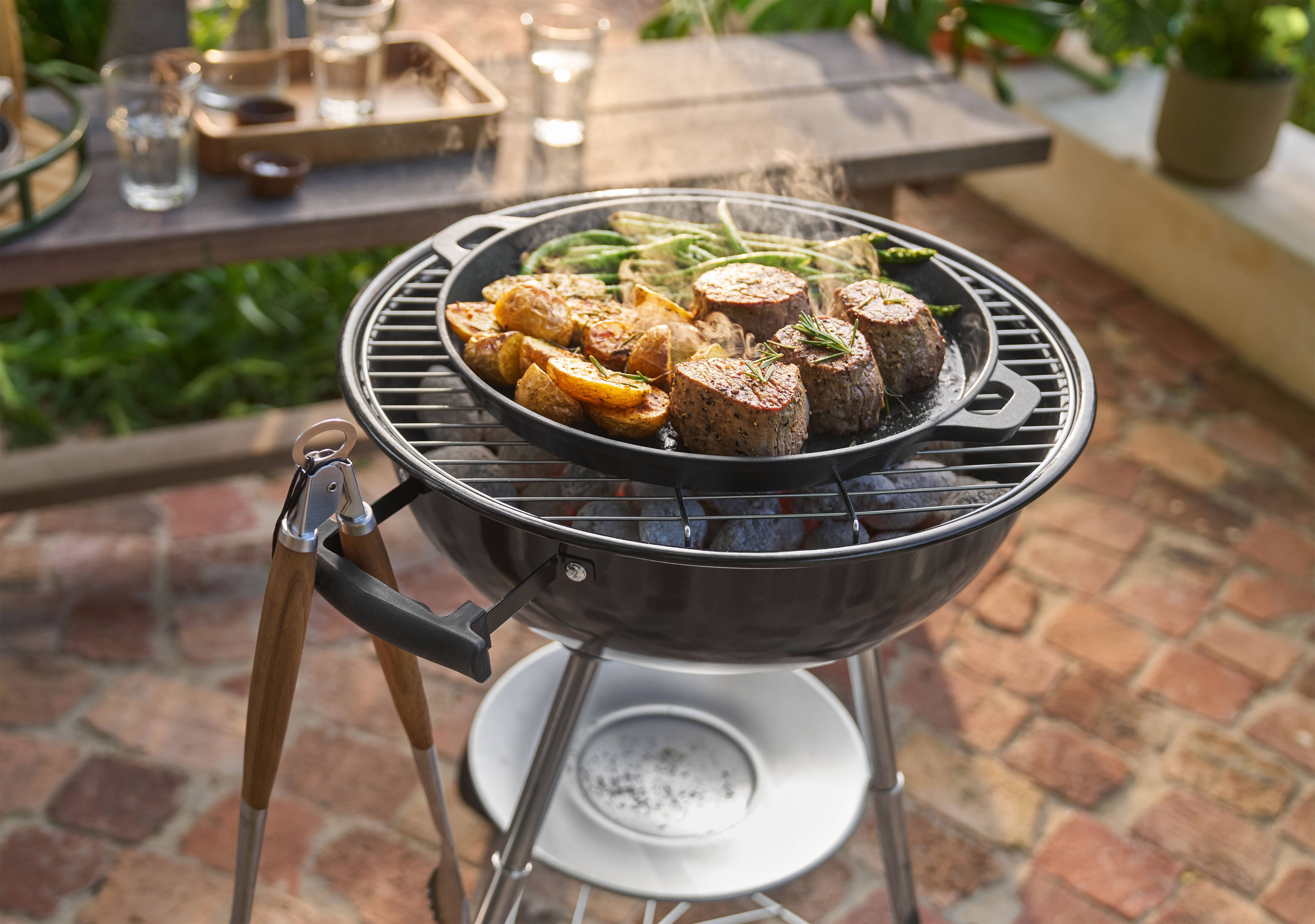 Roštilj sa mesom, krompirom i zelenim pasuljem koji se kuvaju u tiganju napolju.