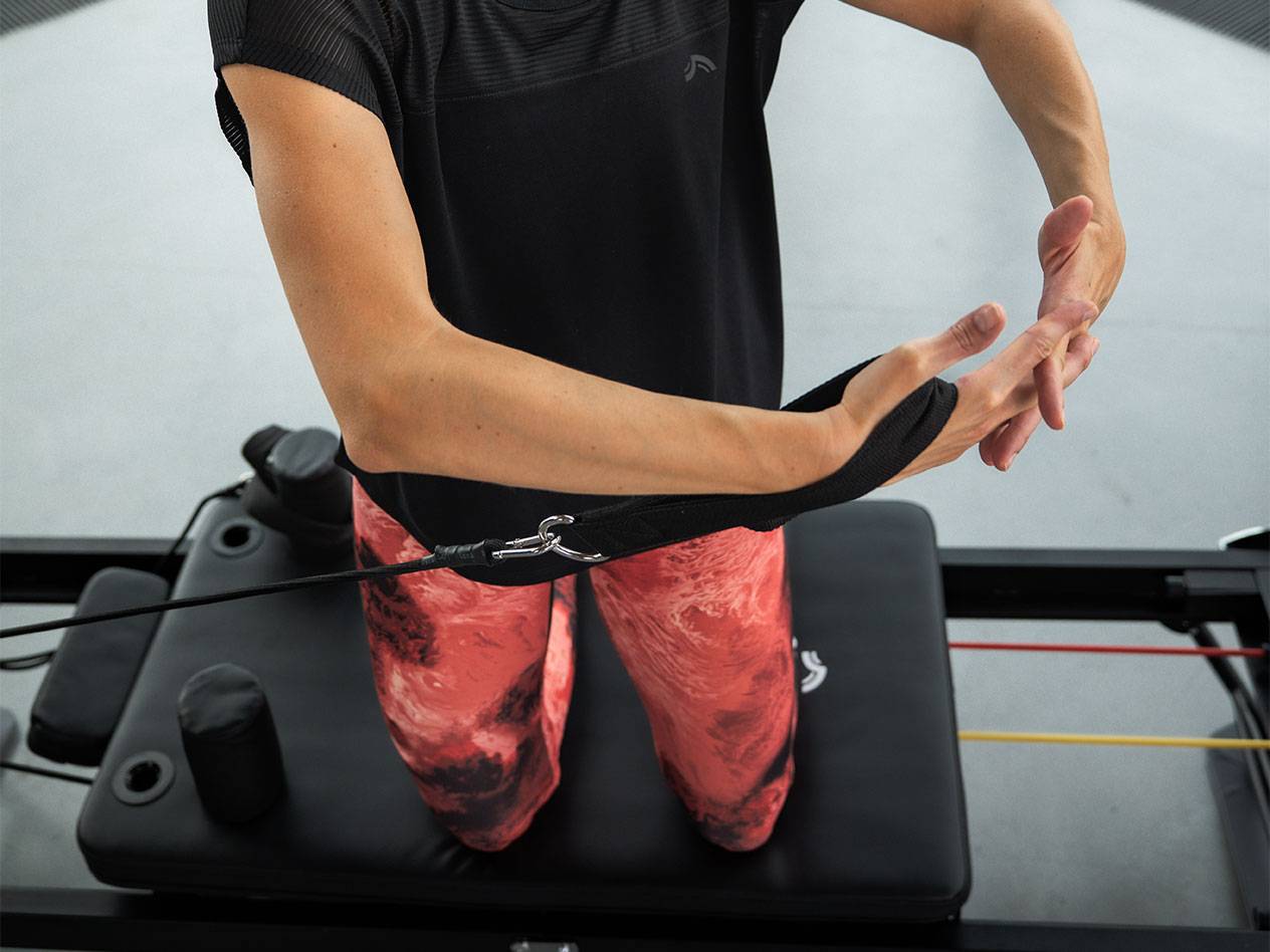 Žena vežba sa trakama otpora na Pilates spravi.