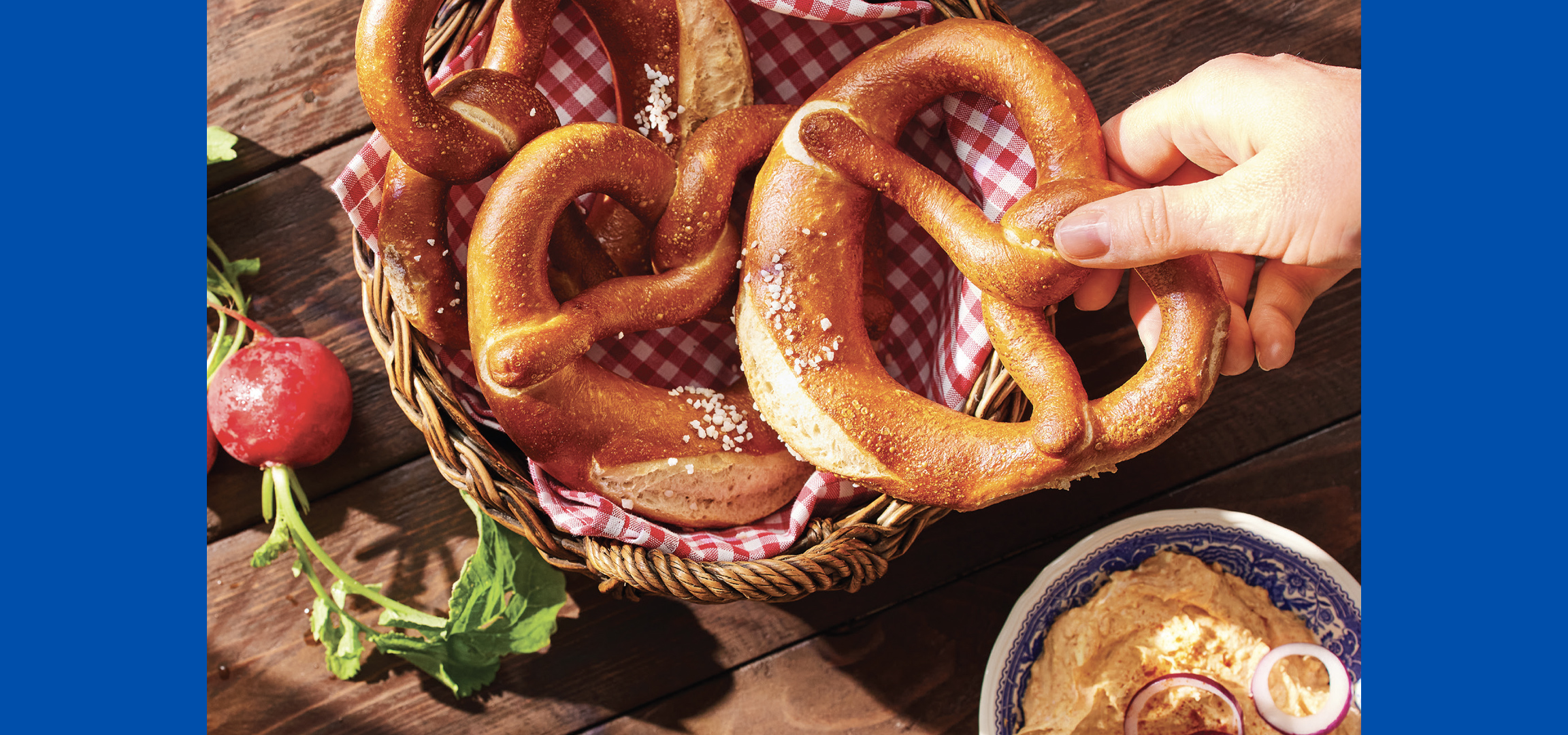 Perece i vafli na kariranom stolnjaku, sa rukom koja uzima perecu i vafle.