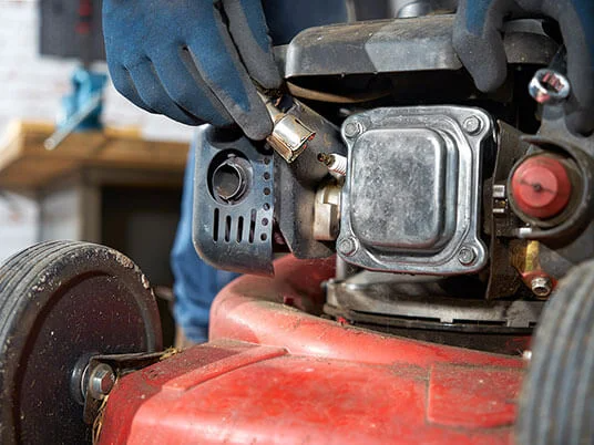 Rukavice menjaju svećicu na crvenoj kosilici.