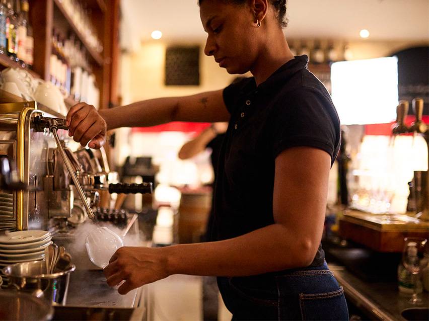 Barista priprema piće sa parom iz aparata za espreso.