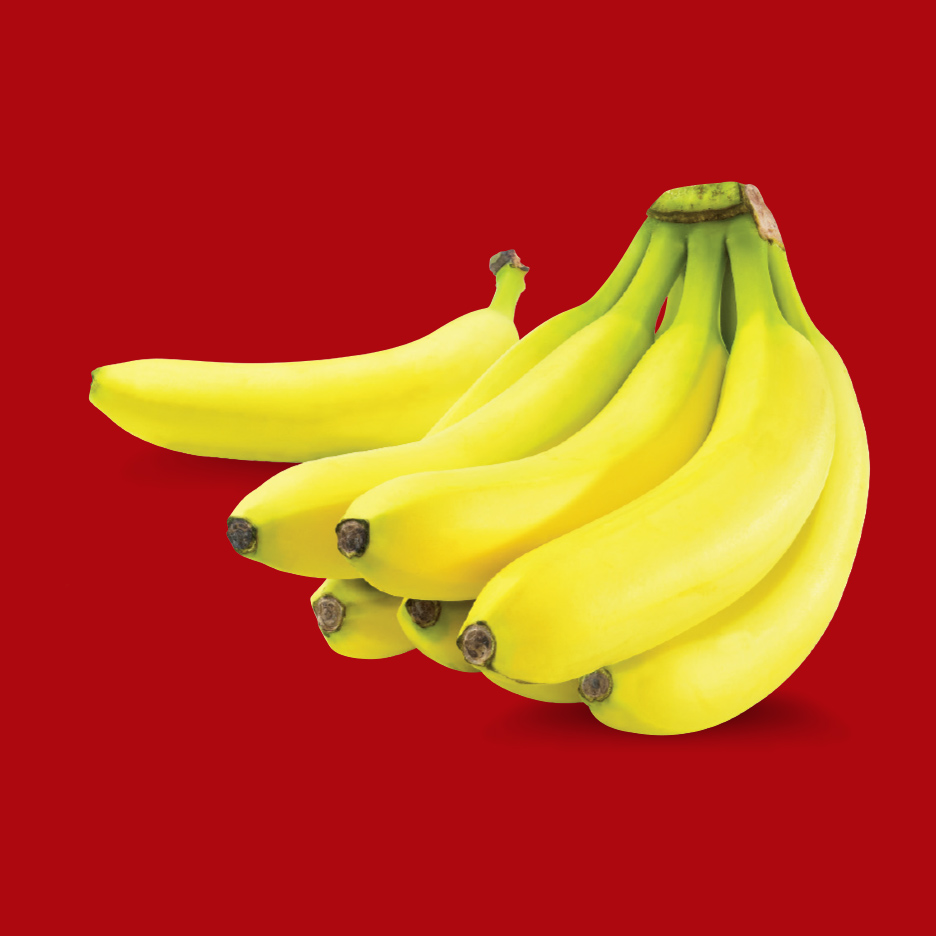 Zreli žuti grozd banana na crvenoj pozadini.