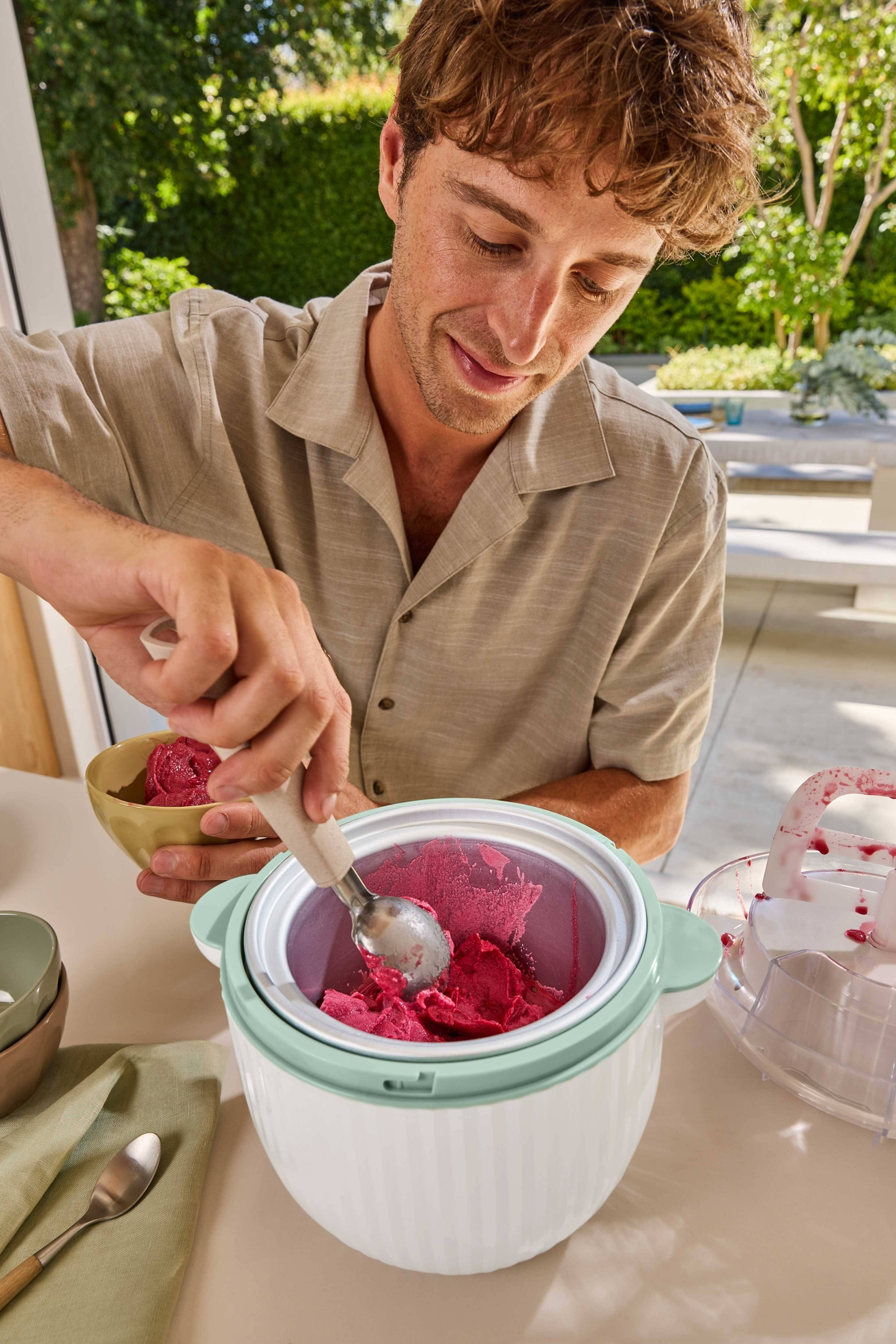 Muškarac vadi crveni sorbet iz aparata za sladoled u činiju.