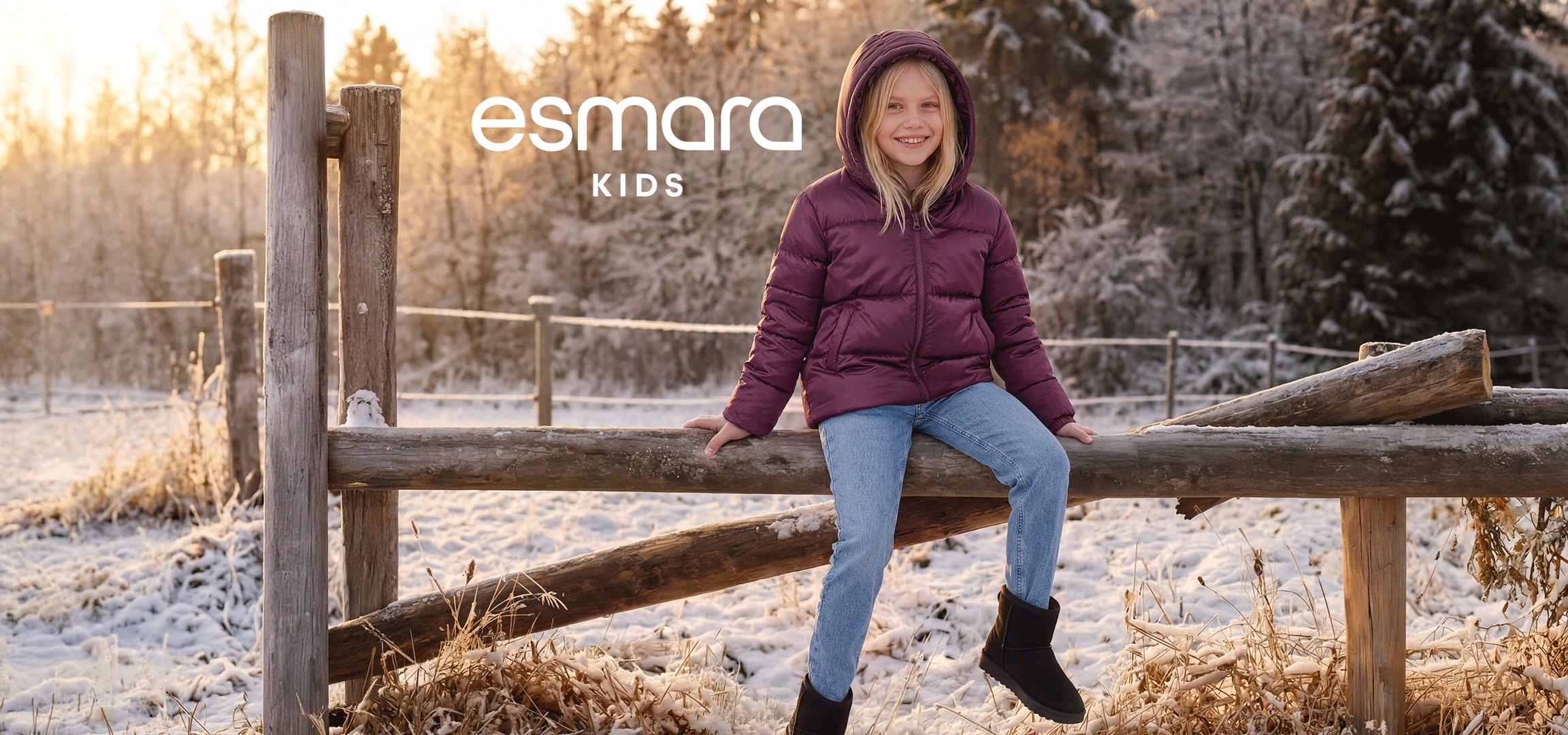 Esmara Kids dečija zimska jakna, farmerke i čizme na devojčici koja sedi na drvenoj ogradi u snežnom predelu