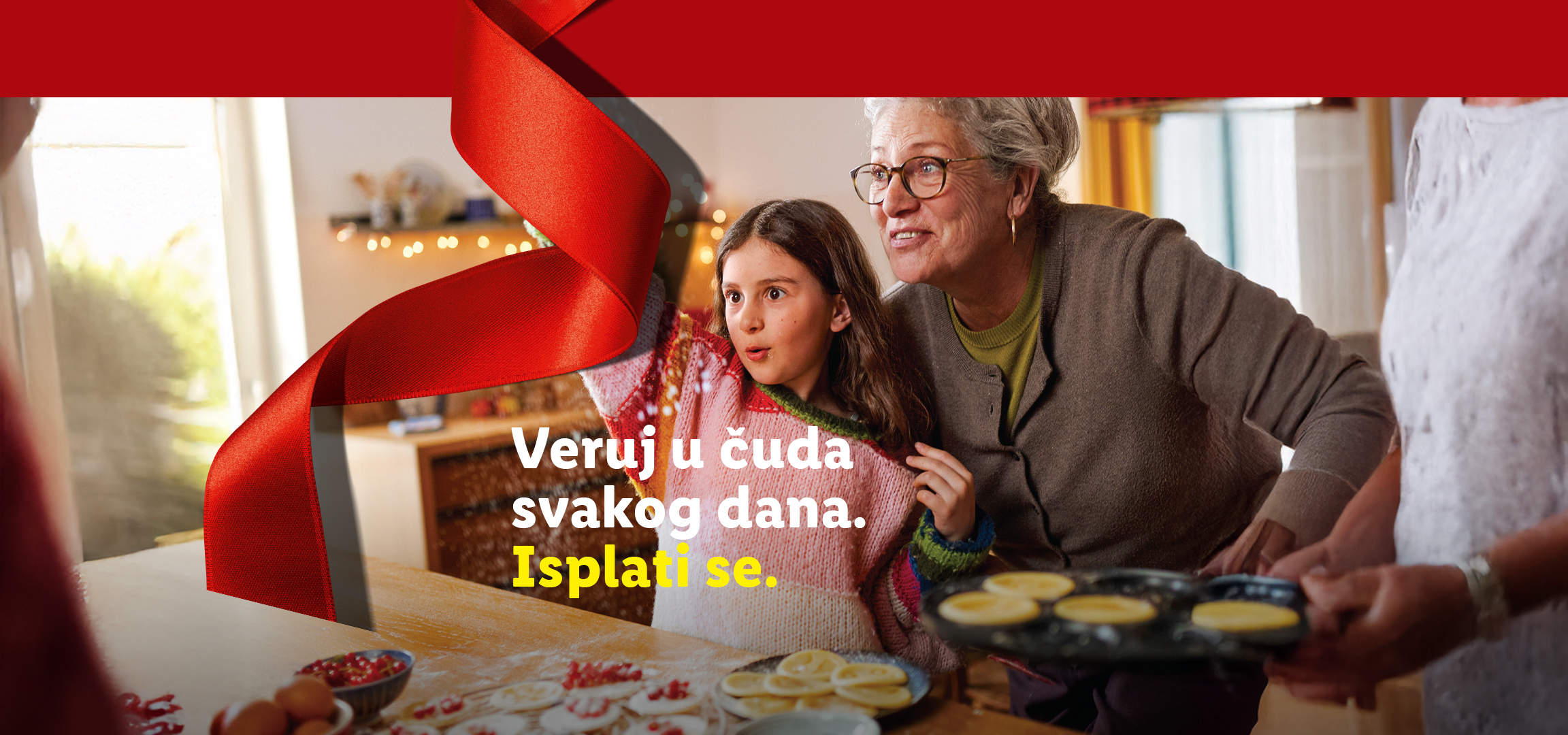 Božićna kugla i baka i unuka koje se igraju sa brašnom. Tekst: Veruj u čuda svakog dana. Isplati se.