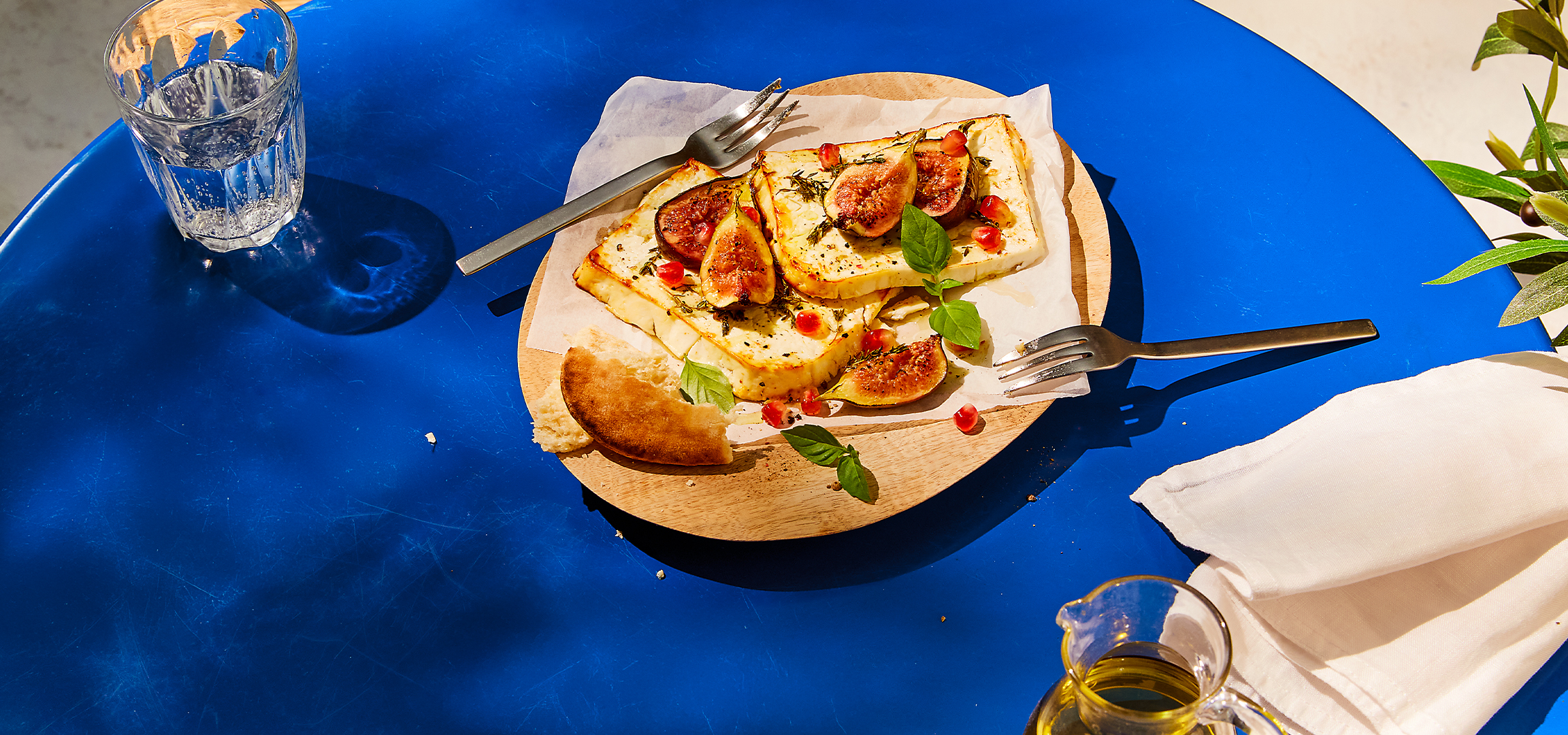 Dva jela na plavom stolu: pečeni sir sa smokvama i narom, i sarmice od vinove loze sa paradajzom.