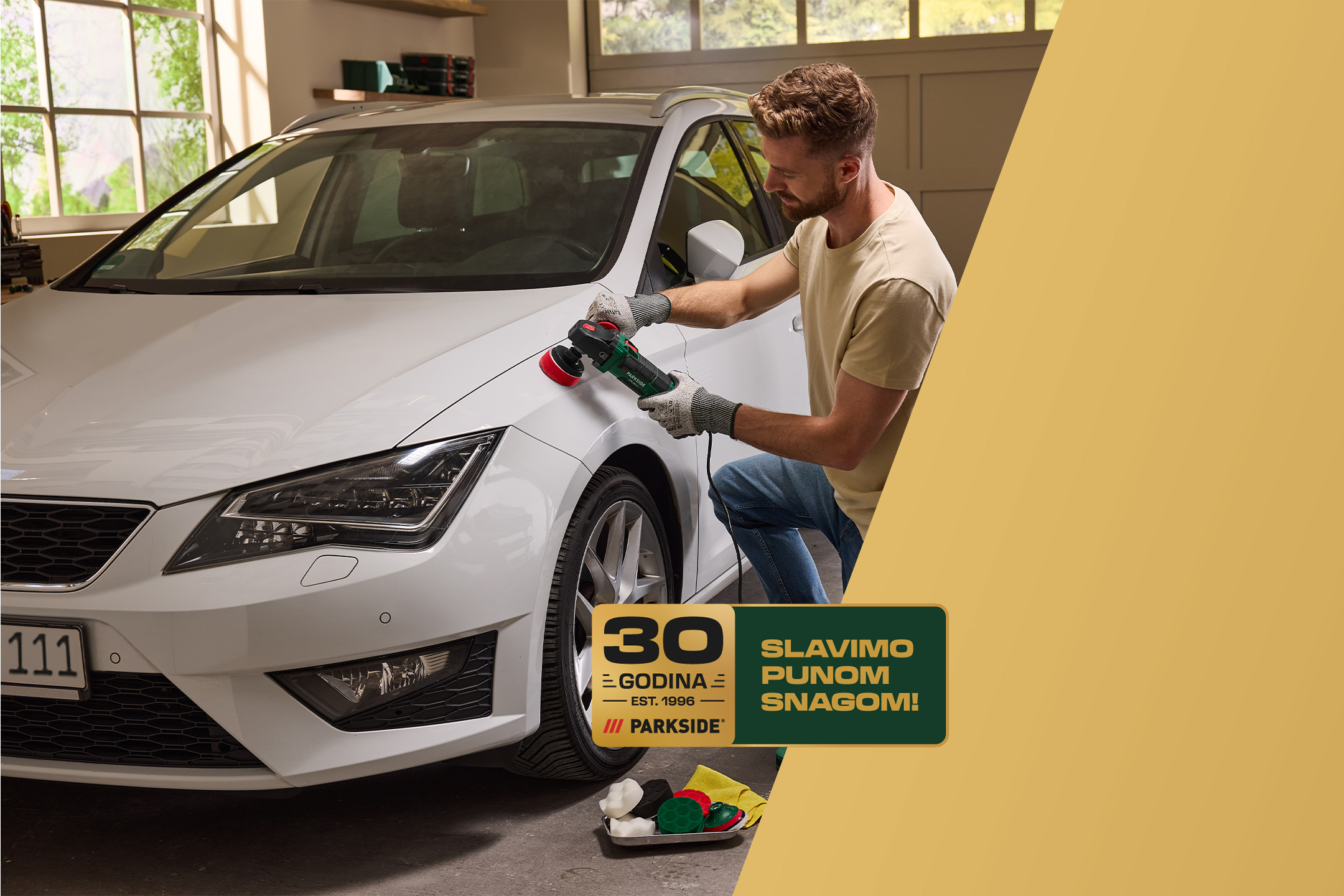 Muškarac polira beli automobil, sa natpisom „30 godina, slavimo punom snagom!“
