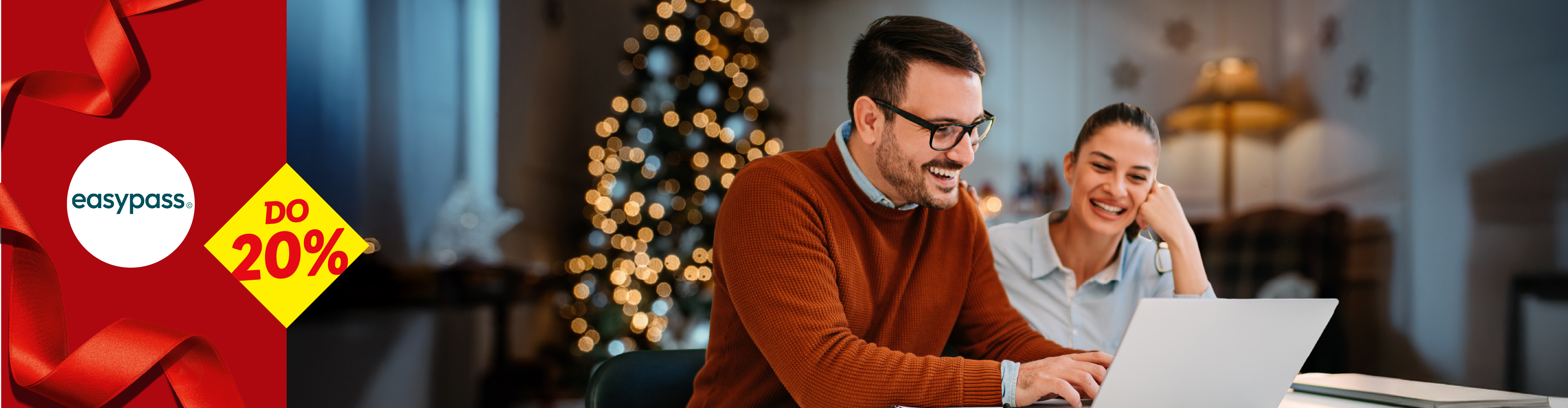 Par se smeje dok gleda laptop, sa božićnom jelkom u pozadini i EasyPass logom sa popustom do 20%.