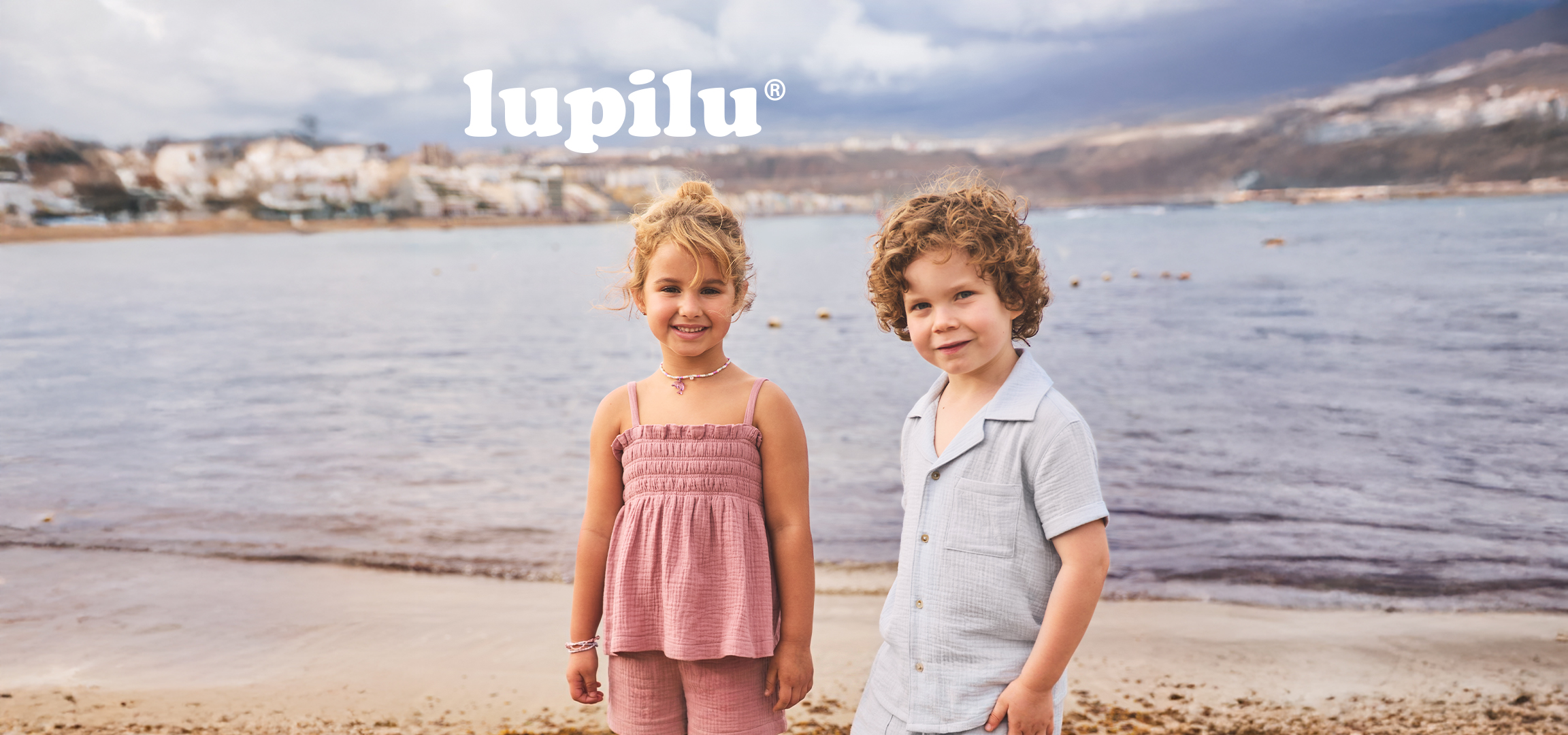 Deca u letnjoj odeći na plaži, jedu dinju, sa logotipom dečije odeće.