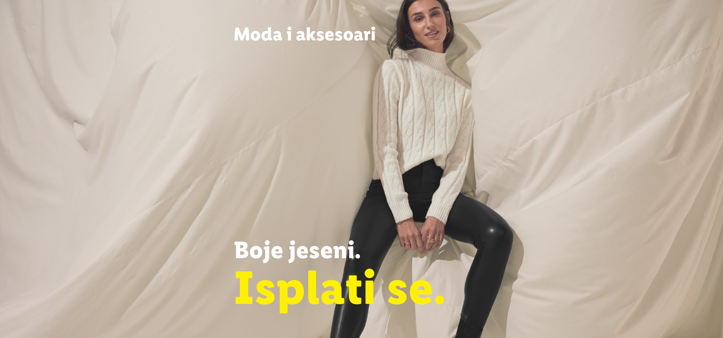 Žena u belom džemperu i crnim pantalonama, jesenja odeća i čizme.