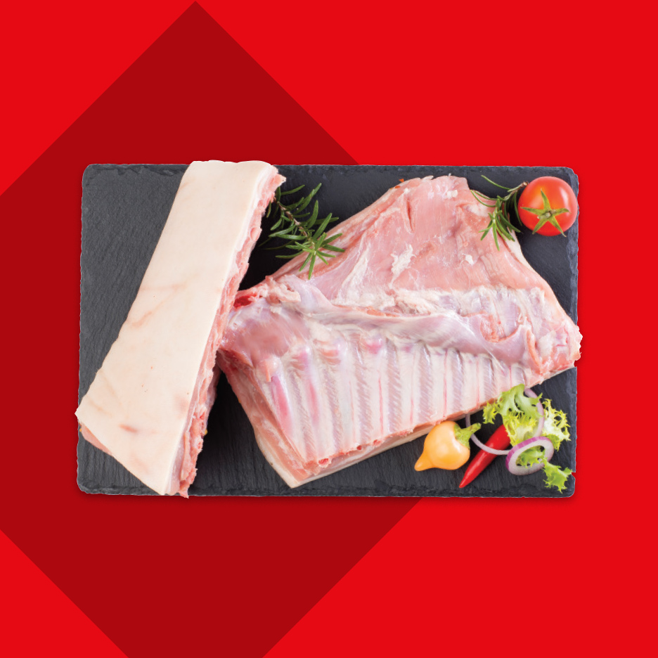 Sveža rebra i slanina na crnoj ploči sa začinskim biljem i povrćem.