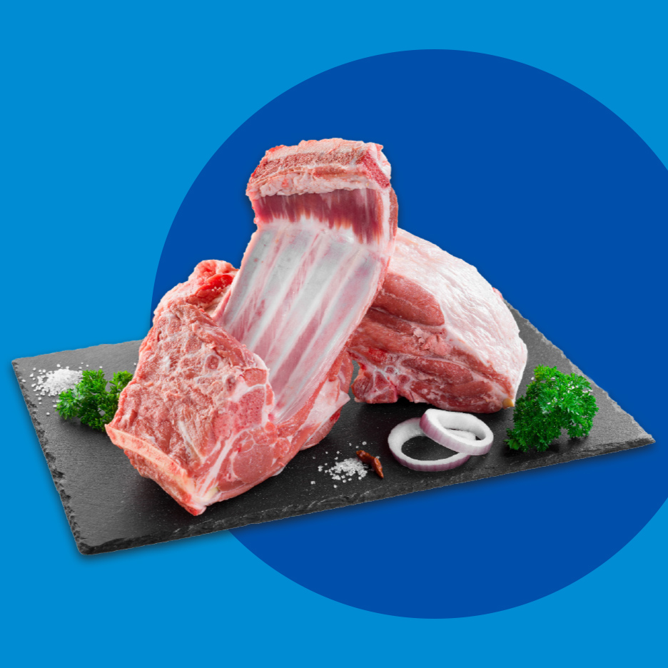 Sveža jagnjeća rebra i meso na crnoj ploči sa začinima i lukom.