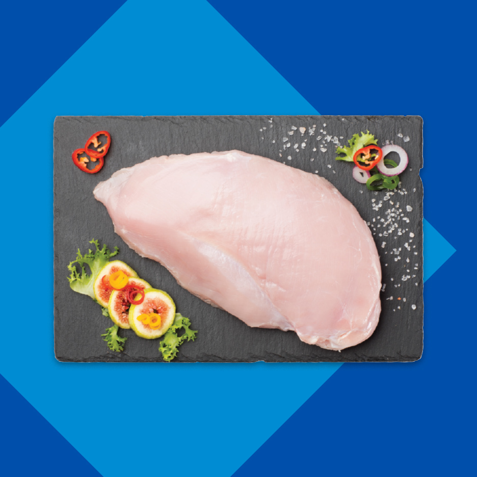 Sveža pileća prsa na crnoj ploči sa začinima i ukrasima.