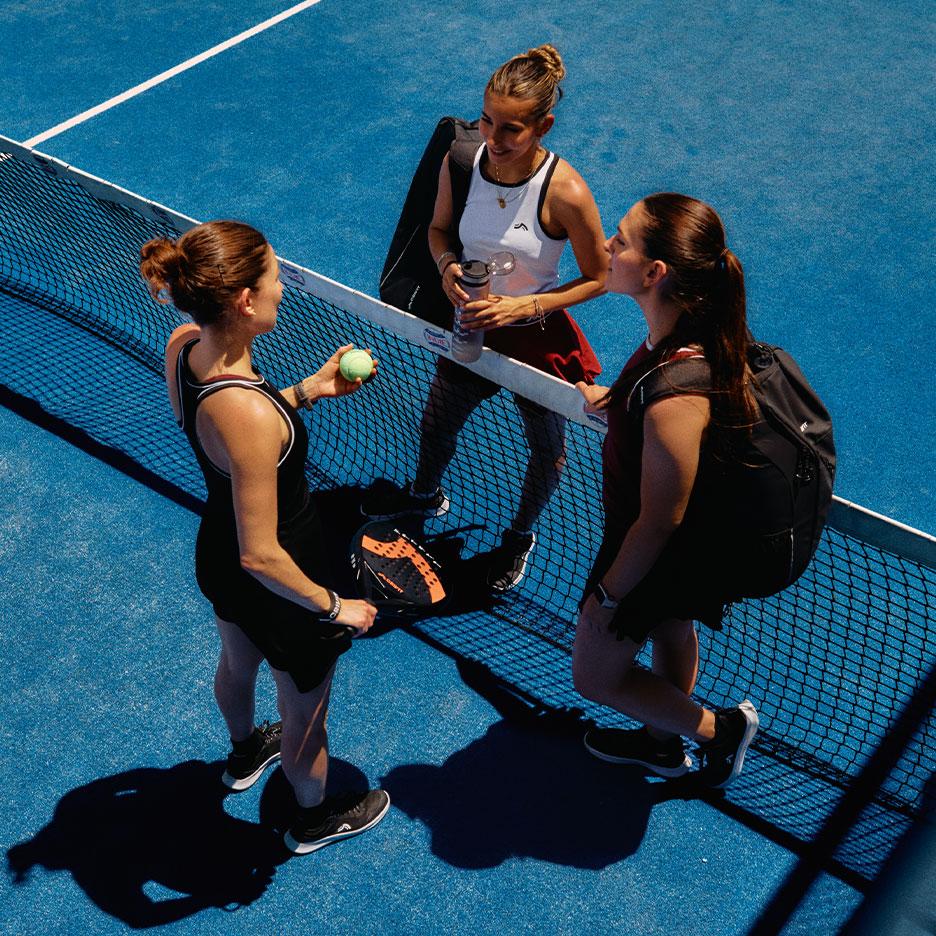 Agostina Bigoti i dve saigračice u CRIVIT sportskoj odeći stoje zajedno kod mreže za padel na plavom terenu nakon meča.