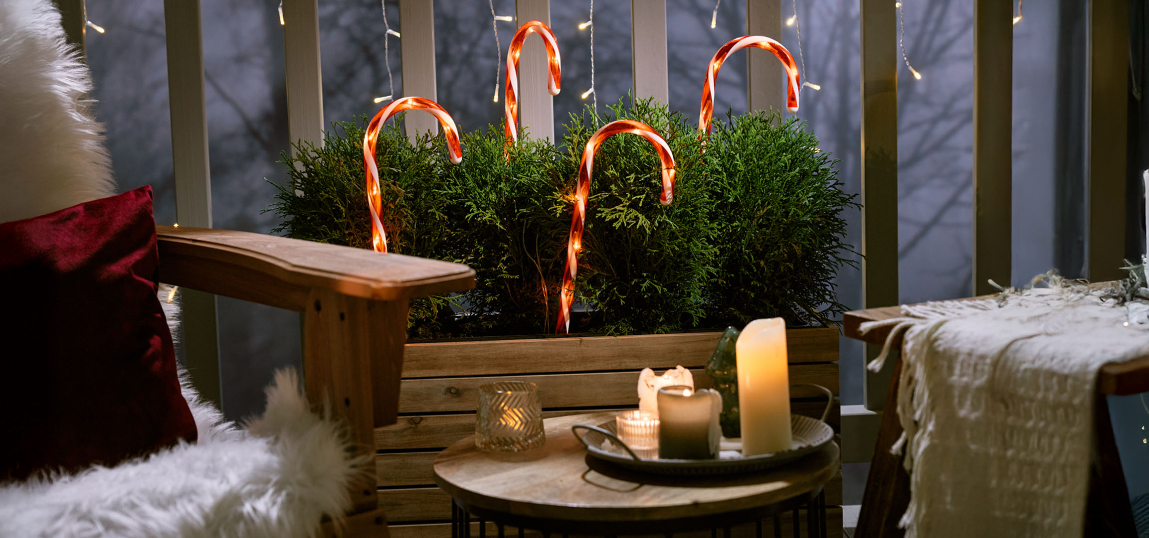 Božićno dekorisan balkon sa stolicom, svećama i štapićima od slatkiša.