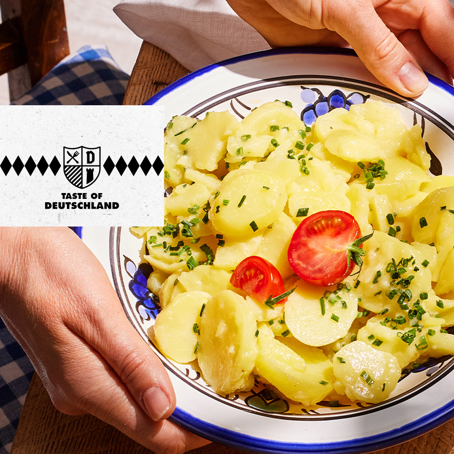 Nemačka krompir salata posuta vlašcem i ukrašena čeri paradajzom.