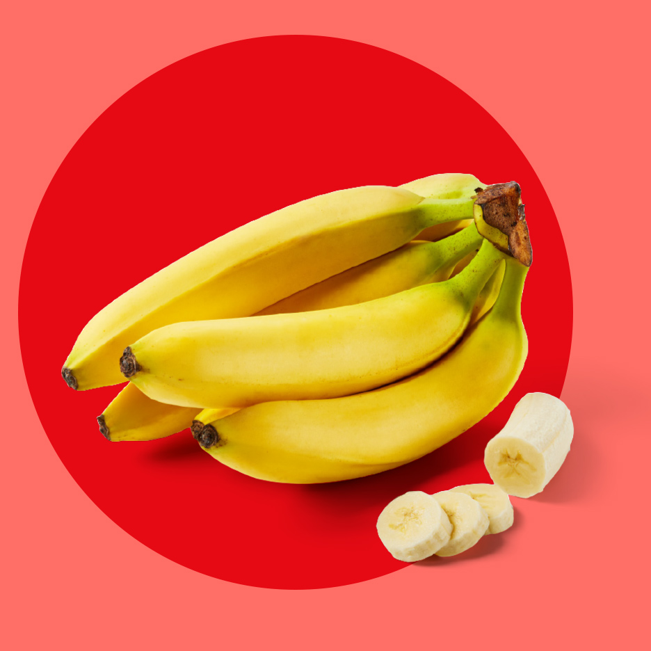 Zrela žuta banana i kriške banane na crvenoj pozadini.