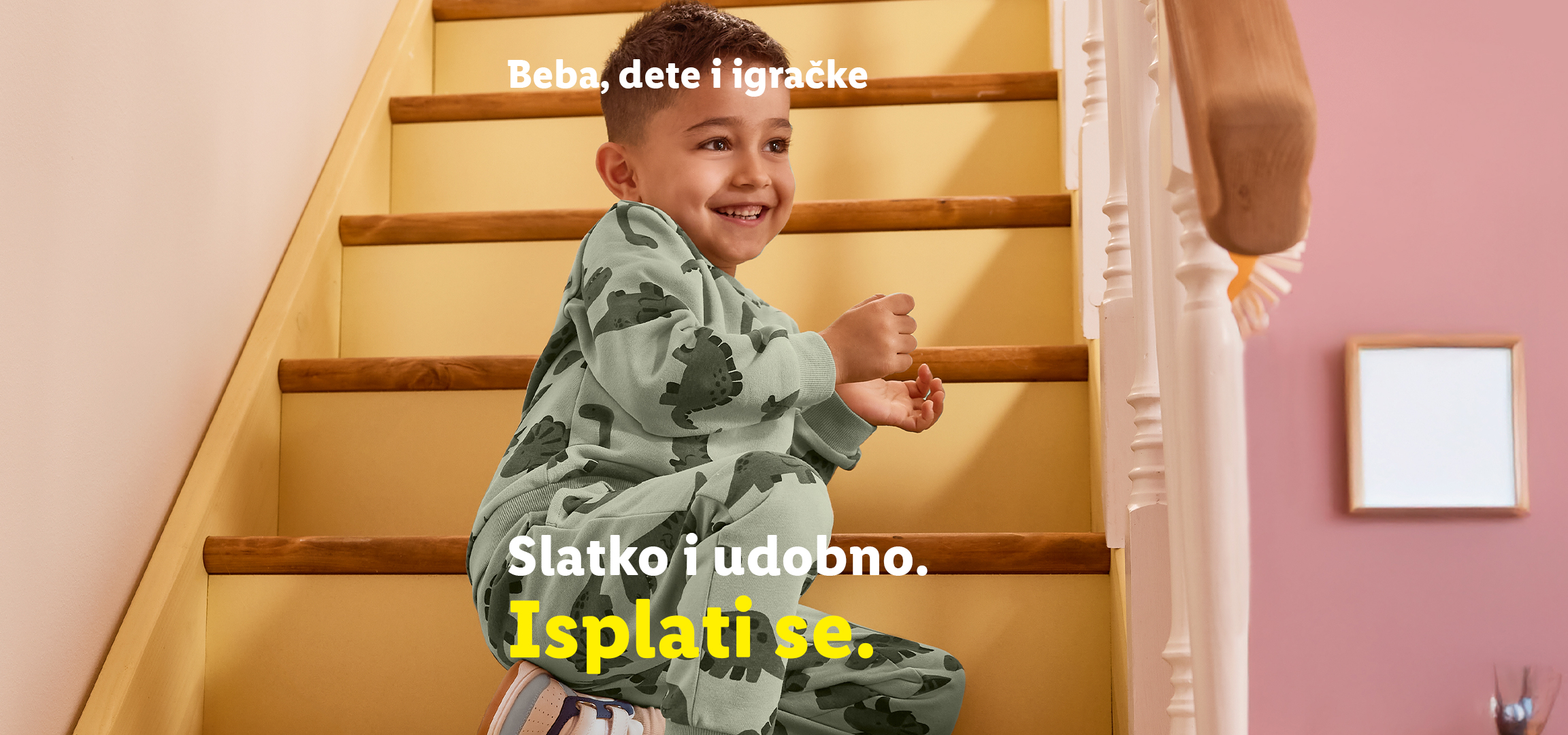 Dvoje dece u pidžamama sa dinosaurima, jedno drži jastuk, drugo sedi na stepenicama. Tekst: Beba, dete i igračke. Slatko i udobno. Isplati se.