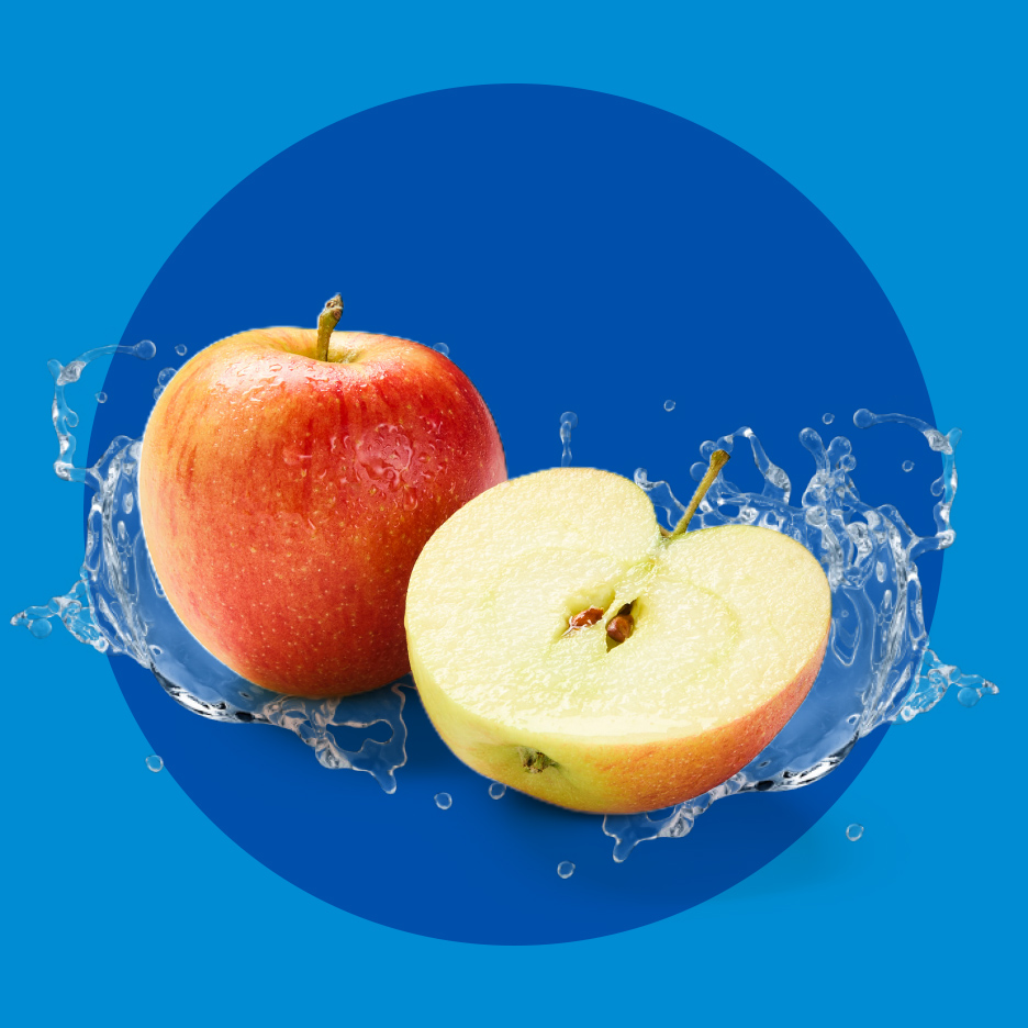 Cela i prepolovljena jabuka sa kapljicama vode na plavoj pozadini.