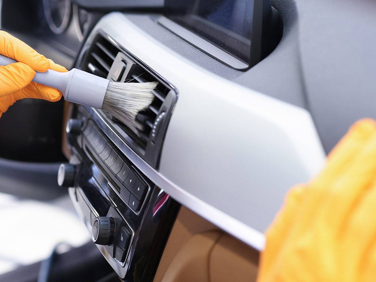 Čišćenje unutrašnjosti automobila četkom za detalje i gumenim rukavicama.
