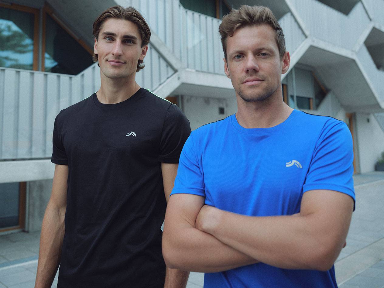 Dva muškarca u crnim i plavim sportskim majicama sa logotipom.