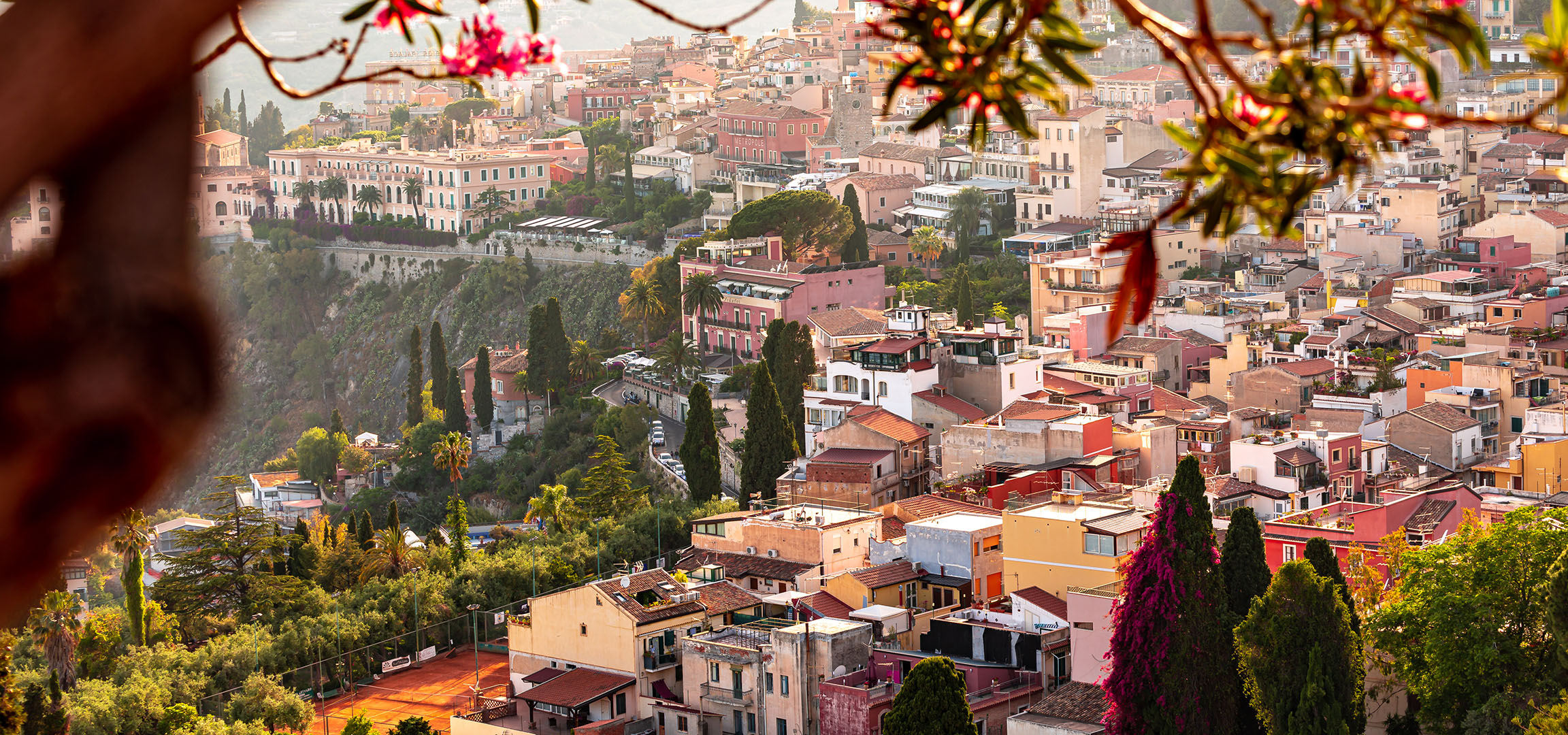 Panoramski pogled na mediteranski grad sa šarenim zgradama i zelenilom.
