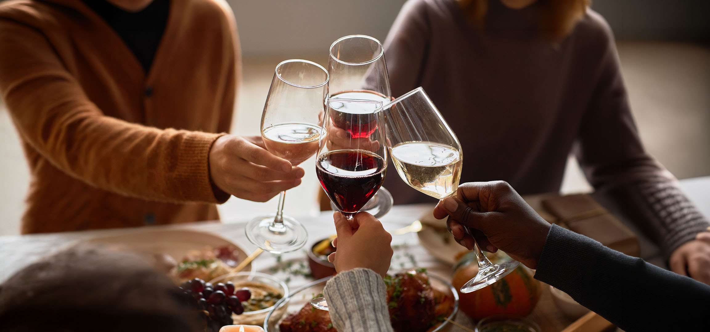 Ljudi nazdravljaju čašama crnog i belog vina.
