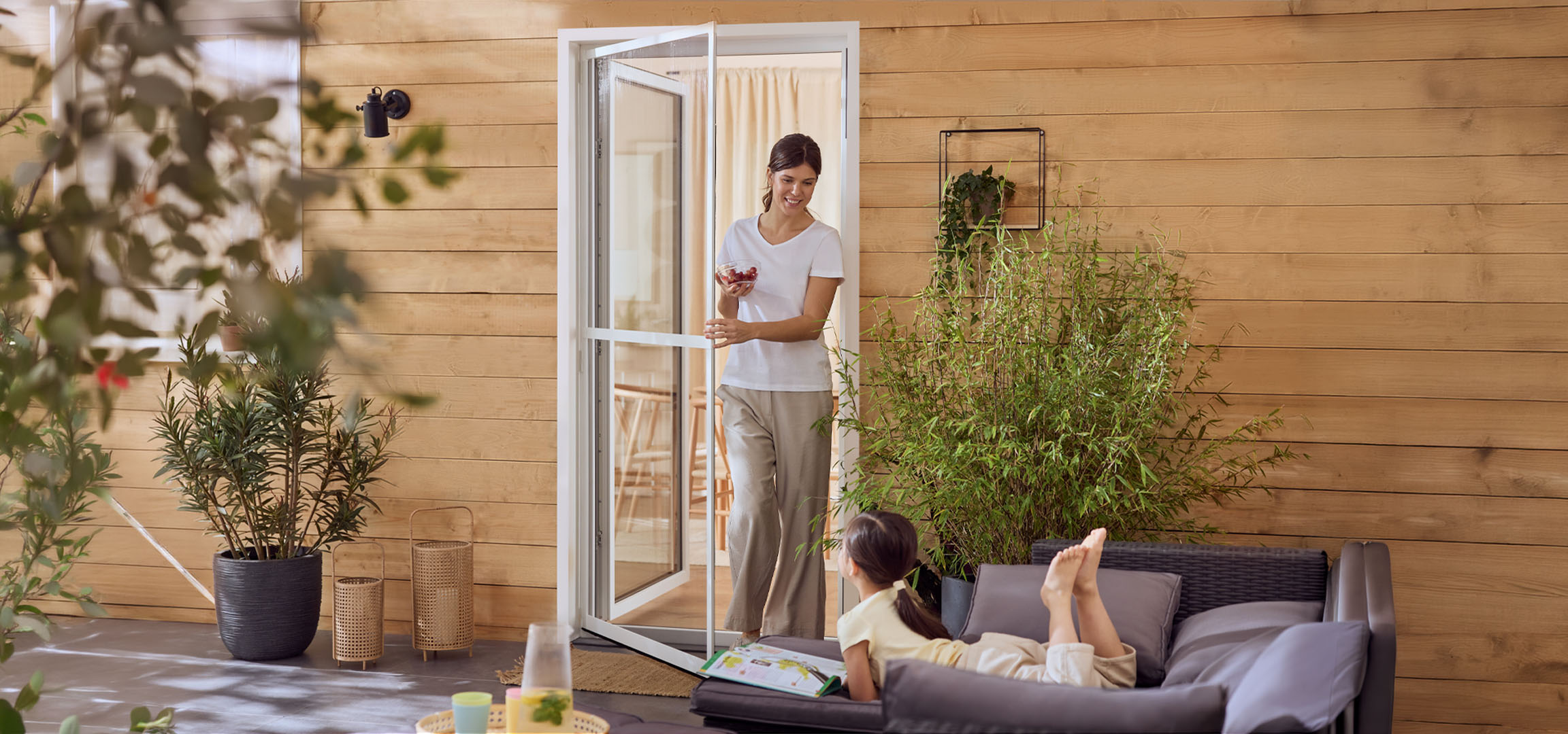 Žena i devojčica uživaju na terasi sa baštenskim nameštajem i biljkama.