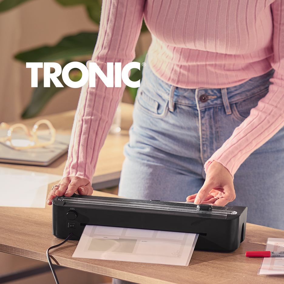 Žena laminira dokumente crnim laminatorom na drvenom stolu.