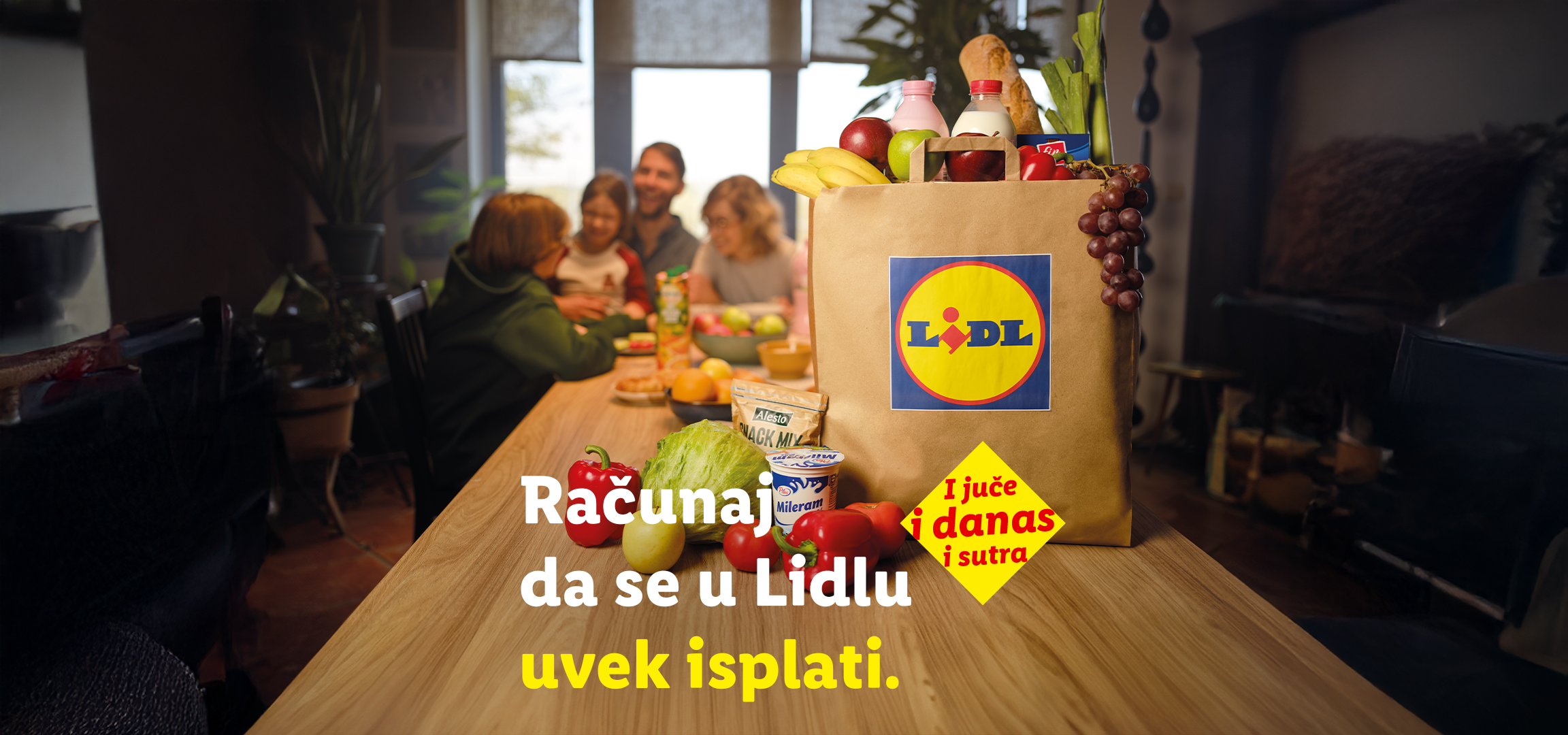Lidl torba puna namirnica na stolu, sa porodicom u pozadini. Tekst: „Računaj da se u Lidlu uvek isplati. I juče i danas i sutra.“