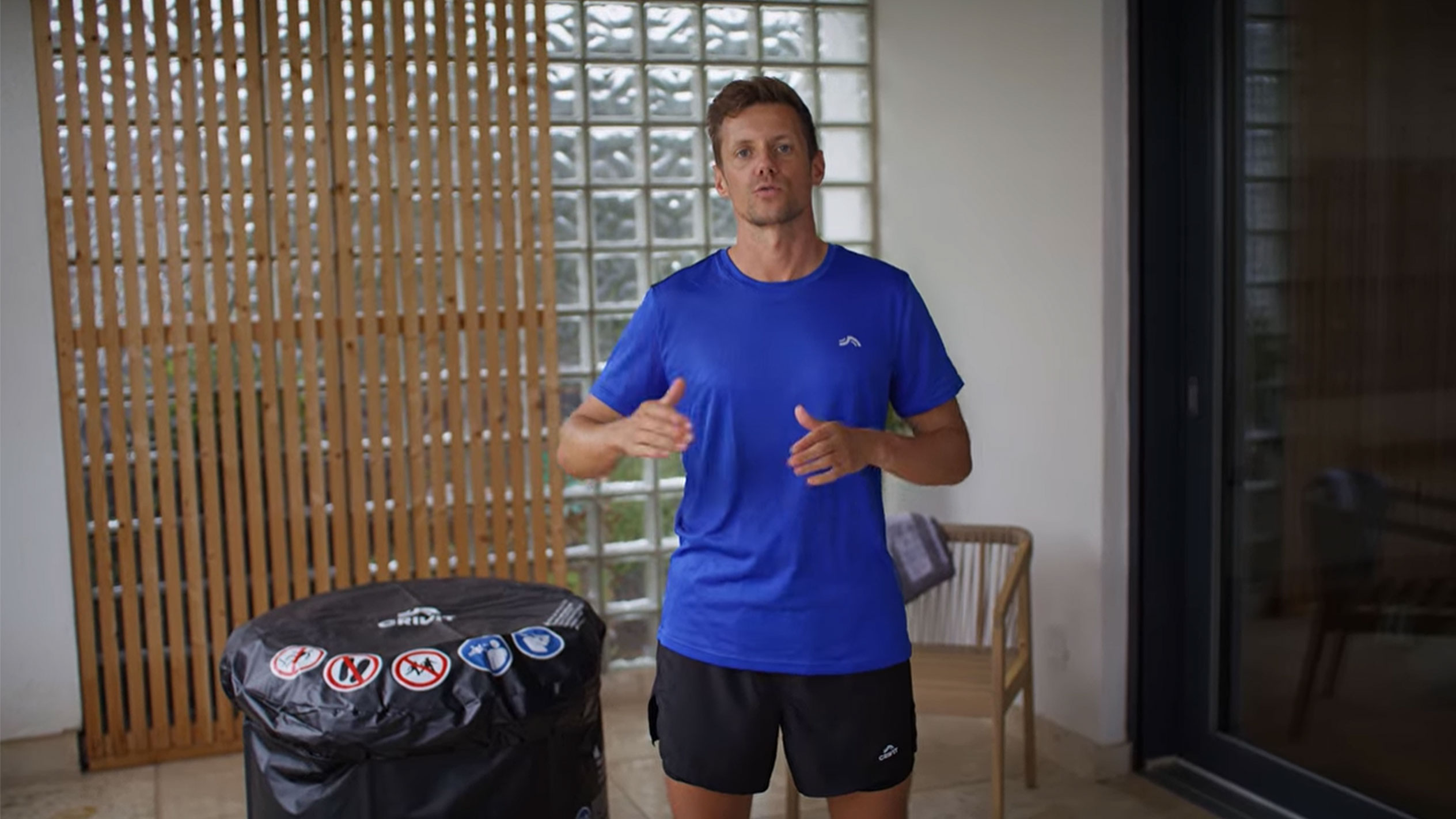 Muškarac u plavoj majici i crnom šortsu, pored crnog poklopca za đakuzi.