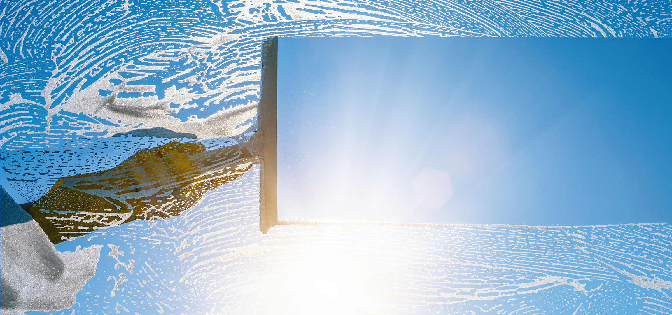 Čišćenje prozora sapunicom na plavom nebu.