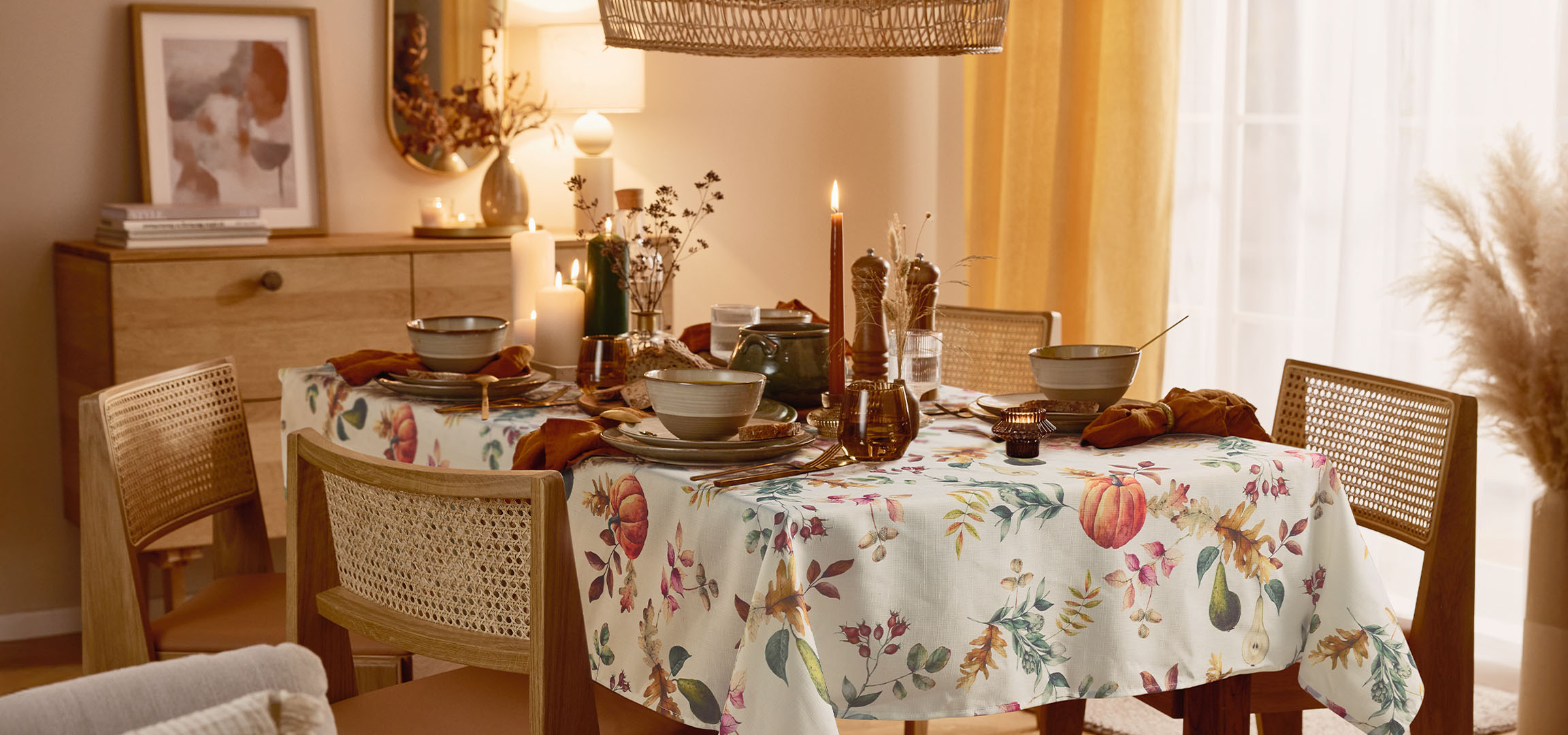 Trpezarija sa stolom postavljenim za obrok, sa cvetnim stolnjakom i toplim osvetljenjem.