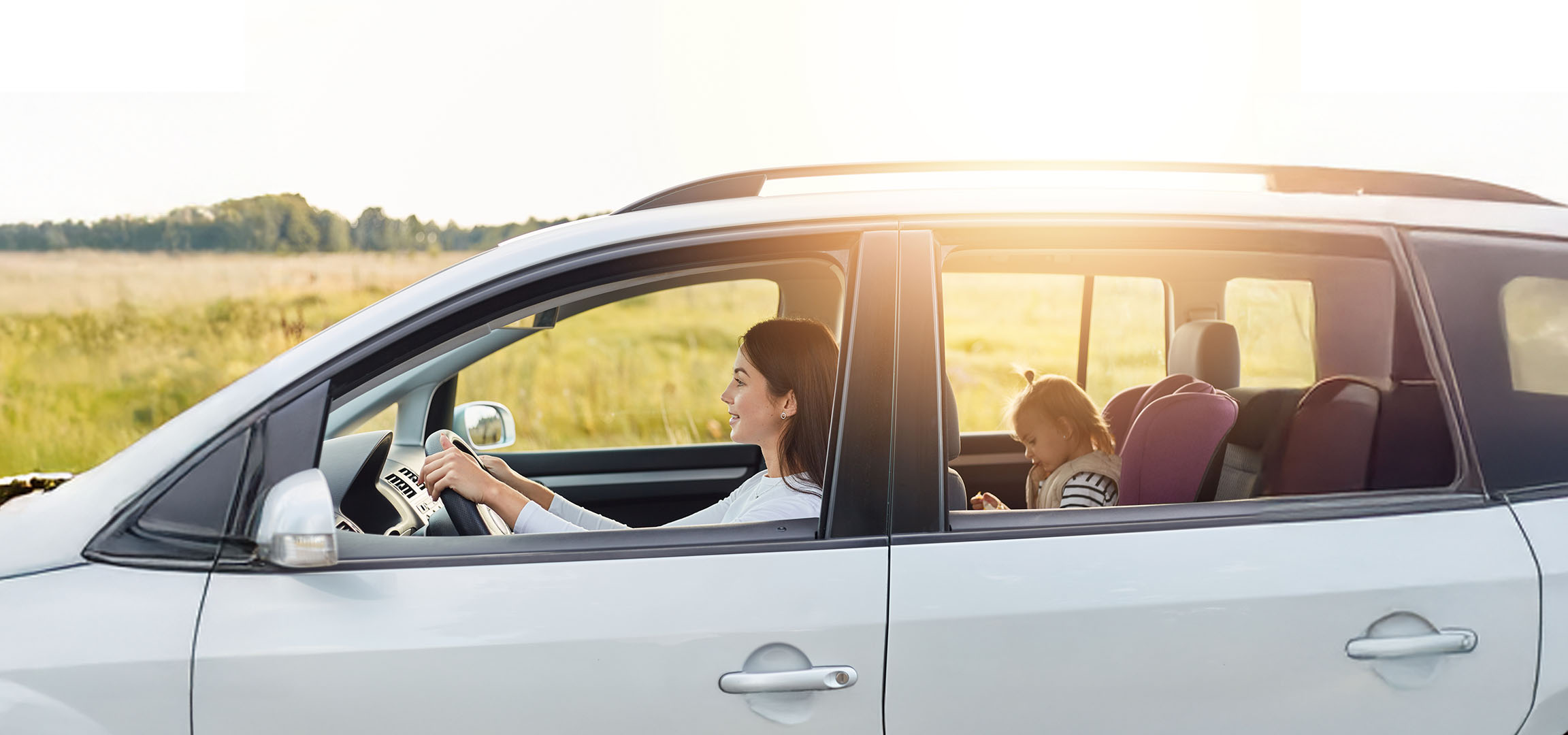 Žena vozi auto, a njena ćerka sedi na zadnjem sedištu.
