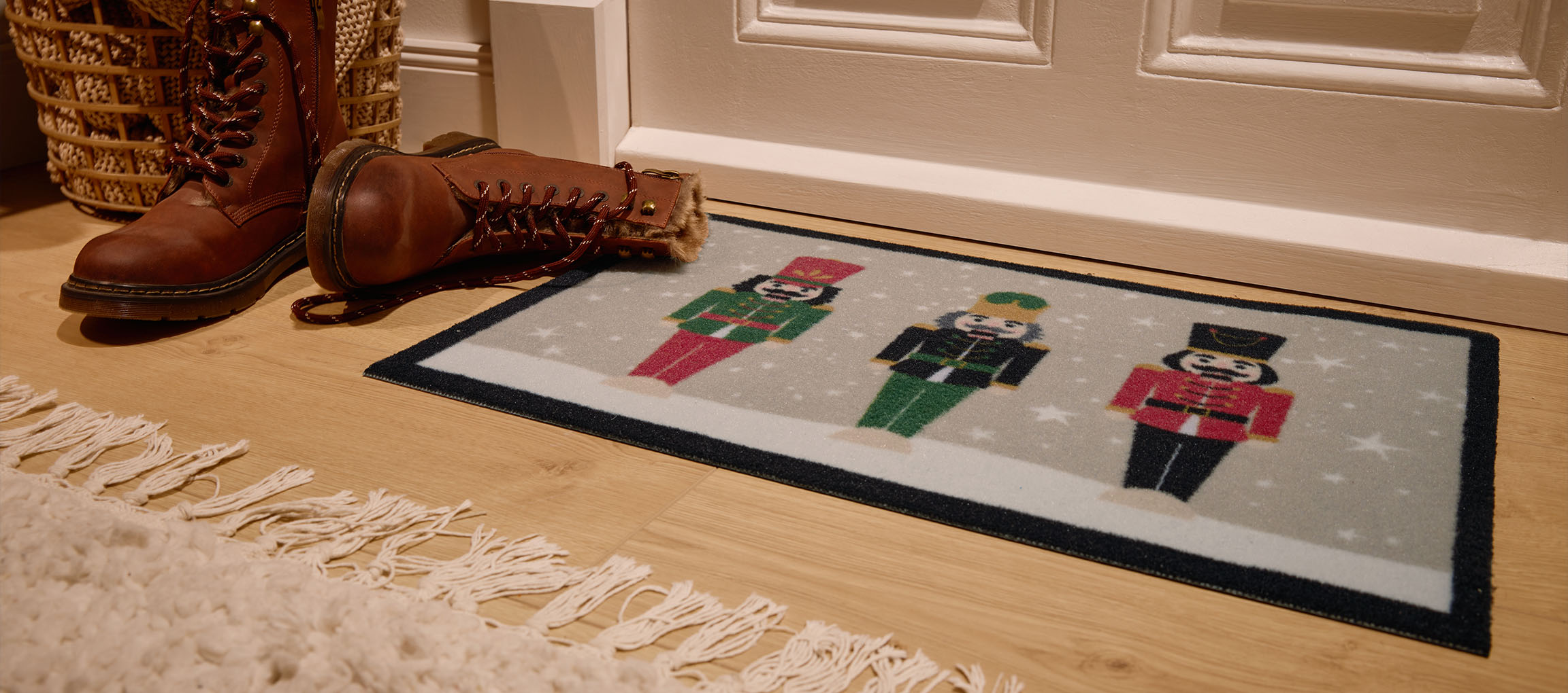 Božićna otirač sa orašarima, braon čizme i pletena korpa na ulazu.