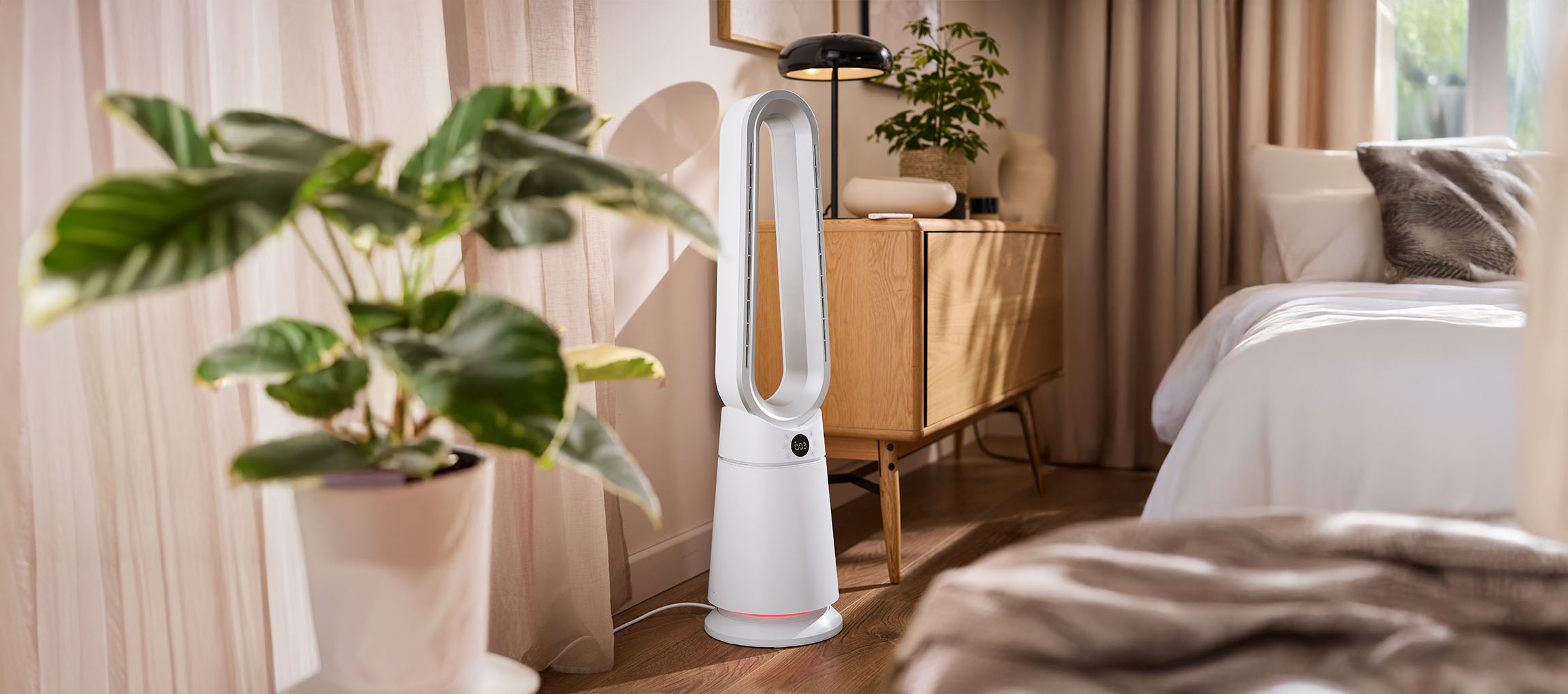 Beli toranj ventilator u spavaćoj sobi sa biljkama i drvenim nameštajem.