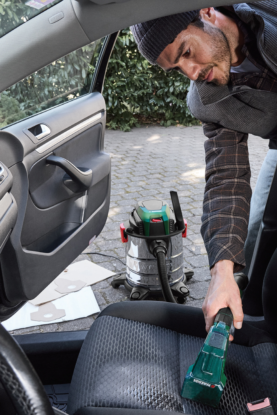 Muškarac čisti sedište automobila Parkside usisivačem za mokro i suvo usisavanje.