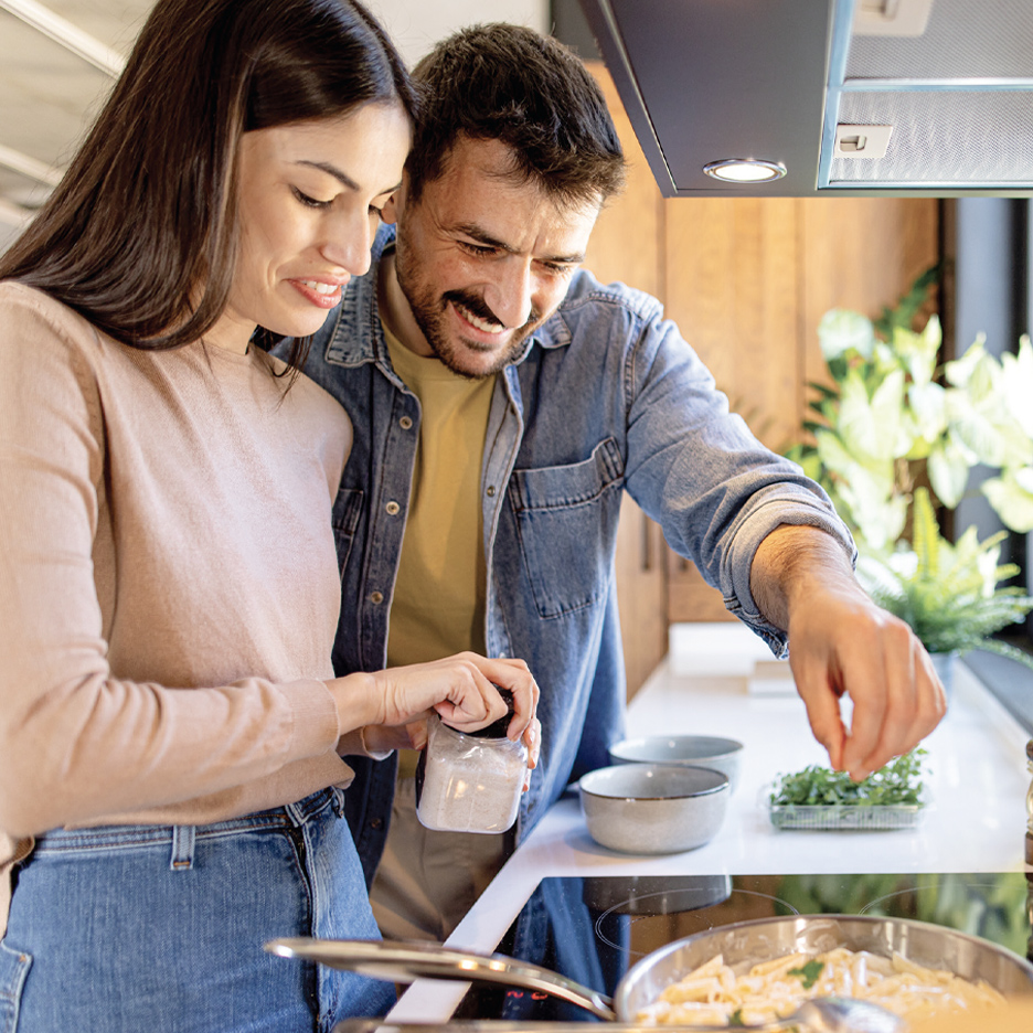 Par kuva testeninu u kuhinji, dodajući začine i začinsko bilje.