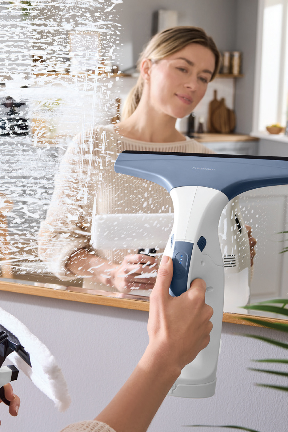 Žena čisti ogledalo bežičnim čistačem prozora i raspršivačem.