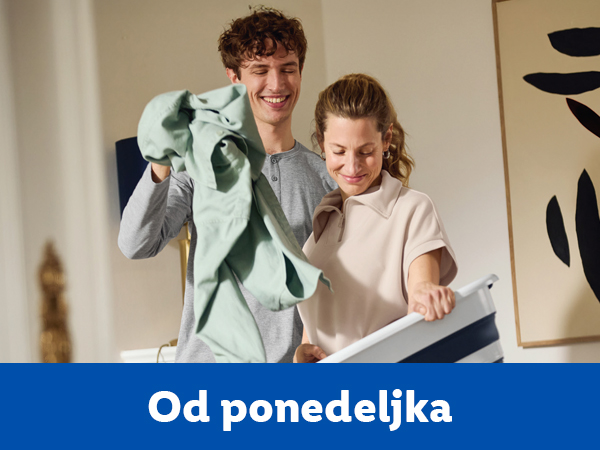 Srećan par slaže veš u korpu za veš.