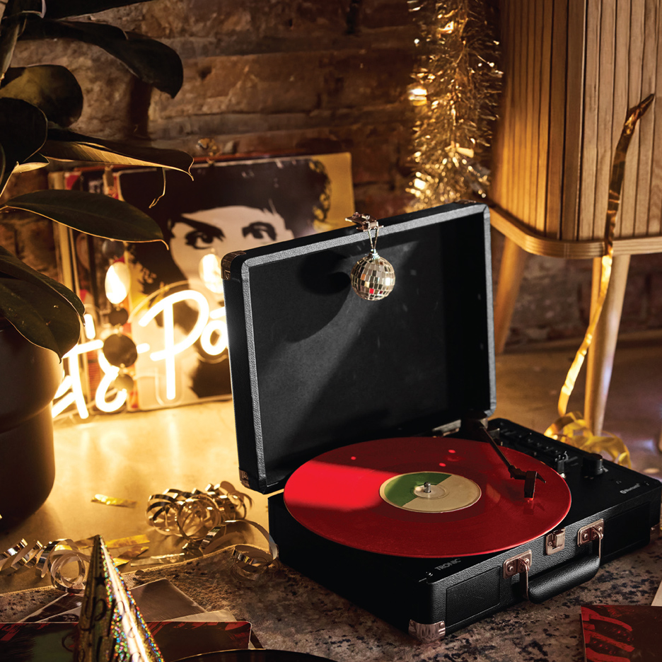 Crni gramofon sa crvenom pločom, disko kuglom i prazničnim ukrasima.